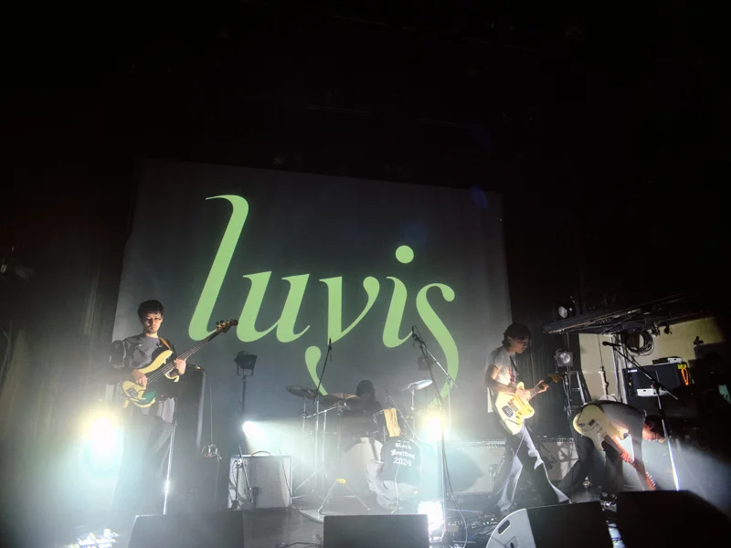 大きなluvisの文字が映るステージで演奏するバンド